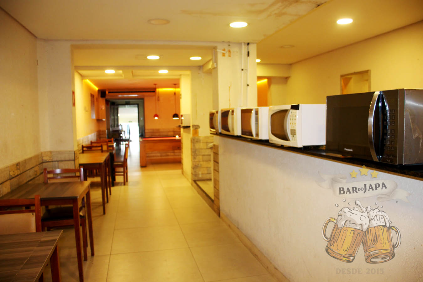 Espaço interno do bar usado para almoço com mesa e micro-ondas